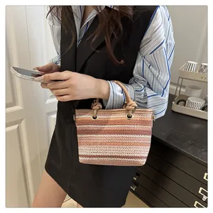 Detail of hand-woven straw tote bag with multi-color stripes and leather trim accents