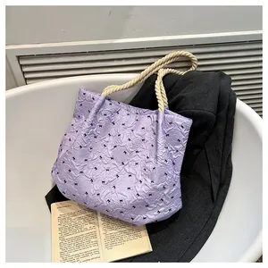 Detail of lavender tote bag with black bows, puckered texture and woven rope handle