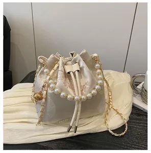 Macro shot of embroidered floral silk fabric and luxury pearl handle on a bucket bag