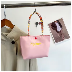 Detail of pink handbag with colorful beaded handle and Fashion Romance embroidery