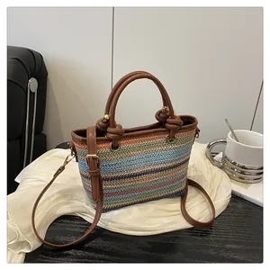 Detail of multi-color striped straw woven tote with leather handles and gold hardware