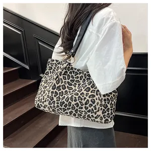 Fashionable leopard print canvas tote bag with black leather straps on a model