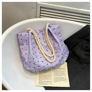 Detail view of purple bow-print tote bag with natural hemp rope handles and crinkled texture