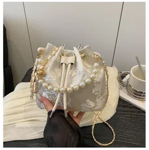 Close-up of floral embroidery on off-white bucket bag with a pearl handle grip