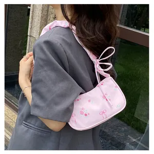 Detail of pink floral canvas shoulder bag featuring rose prints and ribbon bow accents