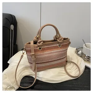 Detail of gradient straw tote bag with knotted faux leather handle and gold hardware