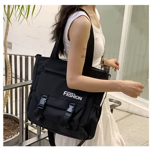 Détail du sac messager en toile noire avec double boucle et lettrage blanc FASHION