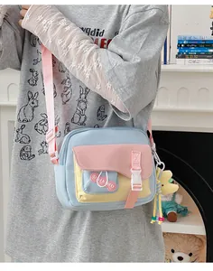 Dettaglio della borsa a tracolla tricolore in nylon con ciondolo peluche e fibbia in plastica