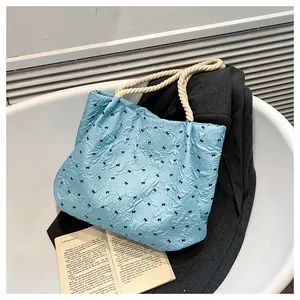 Close-up of light blue pleated tote bag featuring black bow patterns and cotton rope handles