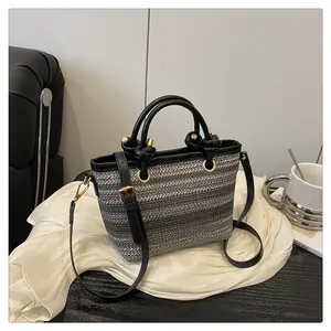 Detail of woven gradient tote with black leather handles and gold-tone hardware