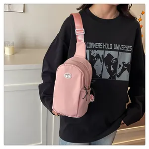 Detail of adjustable nylon strap and oval logo on cream pink sling bag for girls