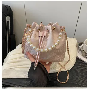 Macro detail of pink jacquard bucket bag with pearl handle and golden chain strap