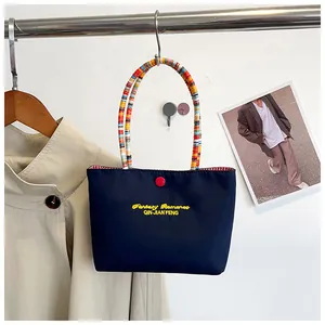 Close-up of a blue tote bag featuring colorful ring handles and yellow embroidery