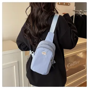 Detail of light blue nylon chest bag with dual zippers and adjustable wide shoulder strap