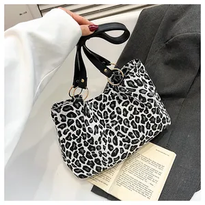 Detail of a zebra print tote bag with black leather straps and gold metal rings