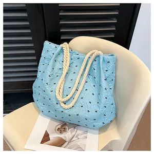 Detail of light blue tote bag with black bow prints and cream rope shoulder straps