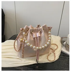Close-up of pink silk bucket bag with floral embroidery and elegant pearl handle