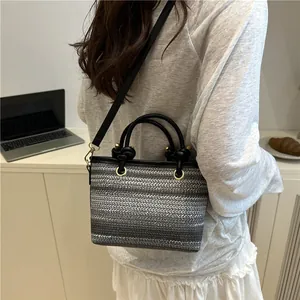 Gray and white striped straw woven bag with leather handles and long shoulder strap