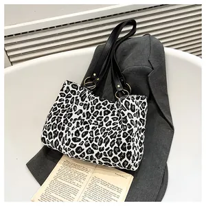 Detail of zebra print canvas tote bag featuring black leather straps and gold rings