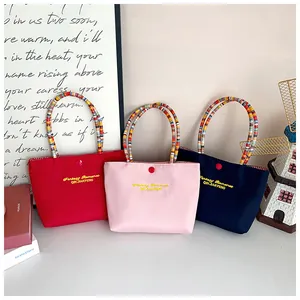 Detailed trio of small tote bags with colorful beaded handles and yellow embroidery