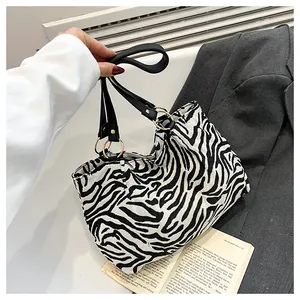 Detail of zebra print tote bag with black shoulder straps and gold metal ring buckles