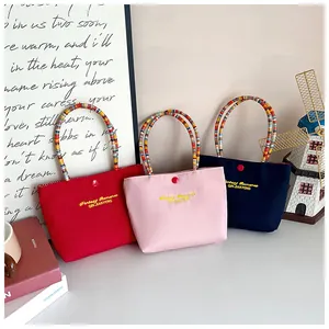 Detailed close-up of embroidered nylon tote bags in red, pink, and navy blue finishes