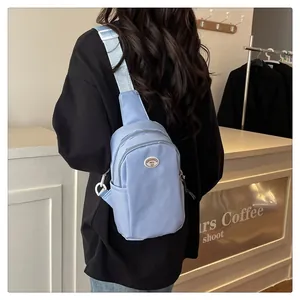 Close-up of light blue nylon chest bag featuring adjustable strap and circular logo