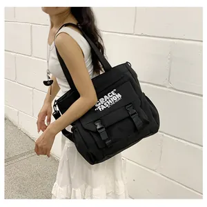 Gros plan sur un sac bandoulière en toile noire avec boucles et texte artistique blanc