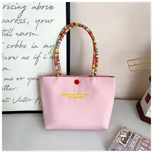 Pink tote bag detail with colorful beaded handle and yellow embroidery text decor