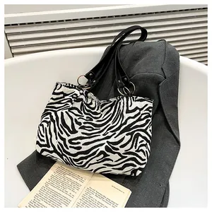 Detail of zebra print canvas tote bag with black faux leather straps and gold metal rings