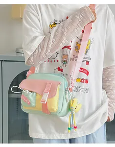Dettaglio di una borsa a tracolla in nylon pastello con tasca a fibbia e ciondolo a stella