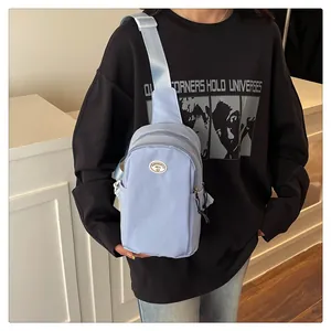 Detail of light blue nylon crossbody bag with adjustable strap and oval logo patch