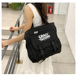Sac bandoulière en nylon noir avec boucles et imprimé lettres porté par un mannequin