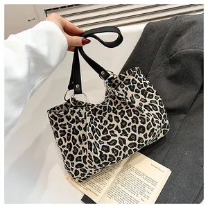 Detail of leopard print tote bag featuring black handles and golden metal ring connectors