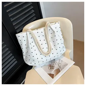 Close-up of white tote bag with black bow prints and textured pleated fabric detail