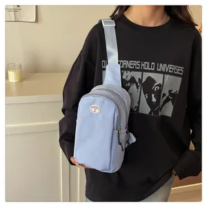 Light blue nylon chest bag shown being worn by a model in a casual home setting