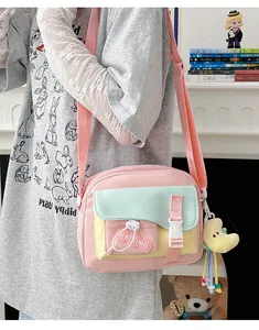 Dettaglio della borsa a tracolla in nylon rosa con tasche a contrasto e un ciondolo luna