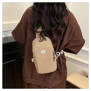 Close-up of beige nylon chest bag with white buckle on waffle textured brown shirt