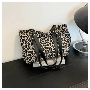 Macro detail of leopard print canvas tote bag with black faux leather strap and gold ring