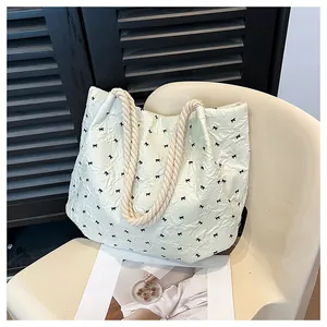 Detail of light green quilted tote bag with black bow print and thick hemp rope handle