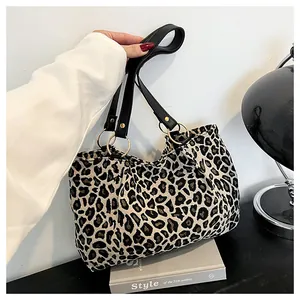 Detail of leopard print canvas tote with black handles and gold metal ring connectors
