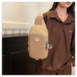Detail of khaki cream chest bag with dual zipper compartments and wide strap