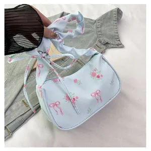 Detail of light blue satin underarm bag featuring pink bows and floral patterns