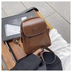 Detail of dark brown vintage mini crossbody bag featuring contrast white stitching