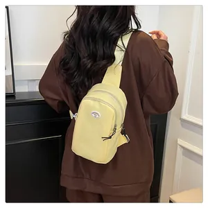 Detail of light yellow nylon chest bag with round fabric patch and adjustable strap