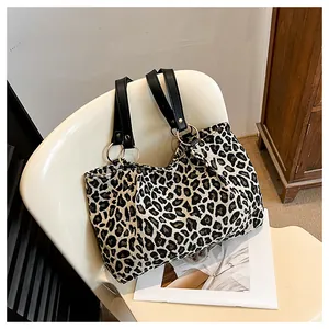Detail of a large zebra print canvas tote bag with black leather straps on a white chair