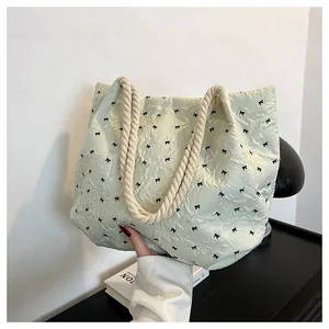 Close-up of light green quilted tote bag with bow embroidery and thick rope handle