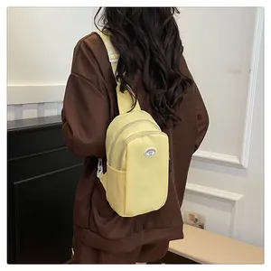 Detailed back view of a cream-colored nylon chest bag worn crossbody by a model