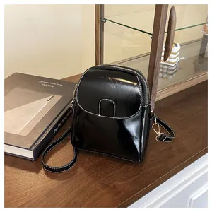 Detail of black PU leather crossbody bag with white contrast stitching and gold hardware