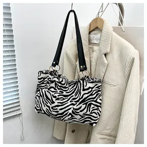 Detail of zebra pattern canvas tote with black leather straps and gold metal rings